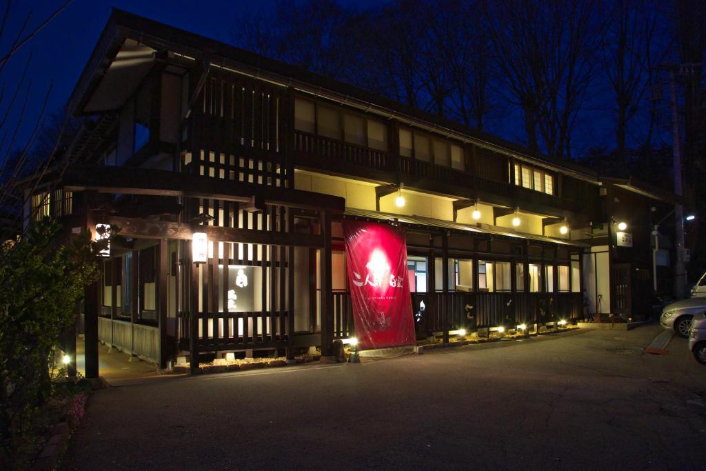 un bâtiment avec un panneau rouge devant lui la nuit dans l'établissement Hidatakayama Futarishizuka Hakuun, à Takayama 37 autres photos