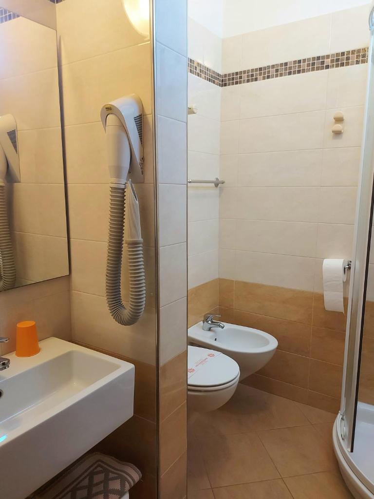 une salle de bain avec un lavabo, des toilettes et une douche dans l'établissement Hotel Monica, à Rimini 95 autres photos