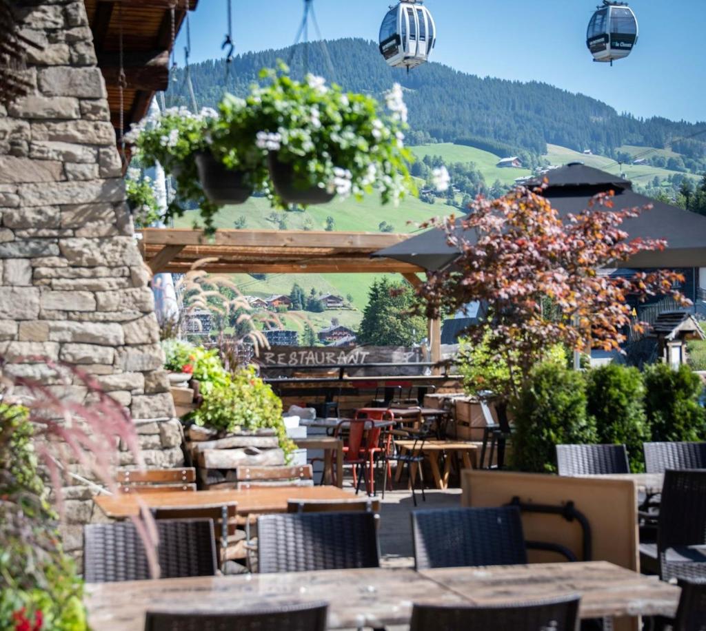 d'une terrasse avec des tables et des chaises et une montagne. dans l'établissement La Ferme, à La Clusaz