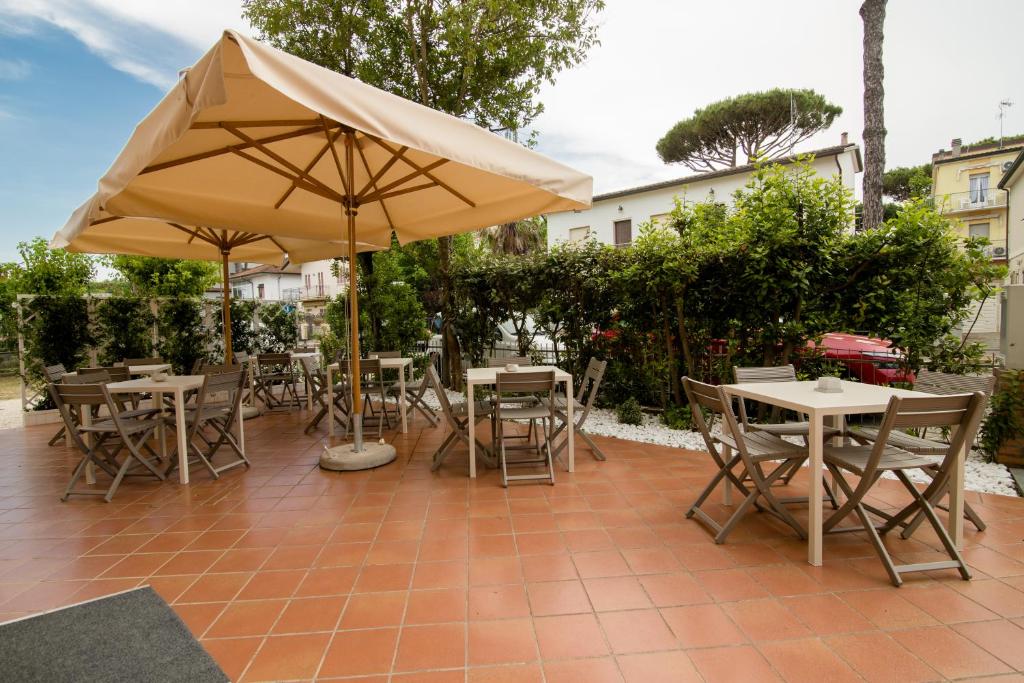 un patio avec tables, chaises et un parasol dans l'établissement Hotel Lydia, à Cervia