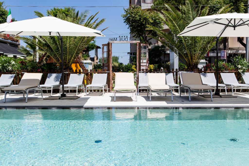 un groupe de chaises et de parasols à côté d'une piscine dans l'établissement Hotel Due Mari & SPA, à Rimini