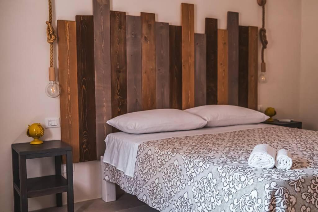 une chambre avec un lit avec une grande tête de lit en bois dans l'établissement Tenuta Trullo Acquaro Ostuni, à Ostuni
