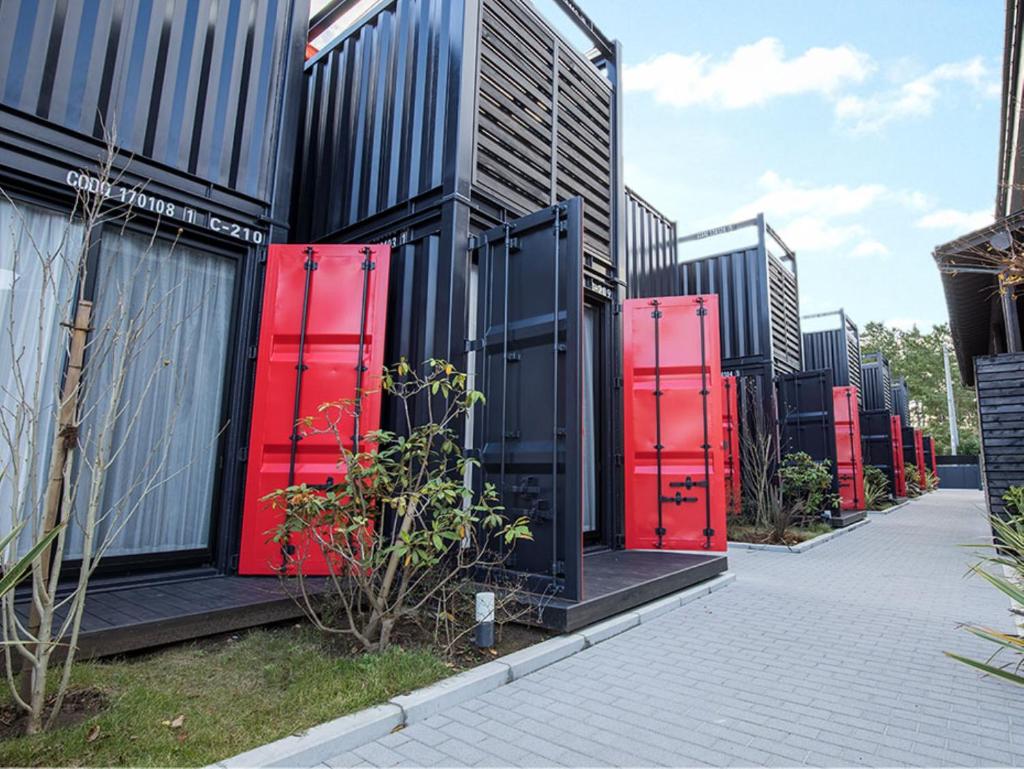 une rangée de portes rouges sur le côté d'un bâtiment dans l'établissement HOTEL R9 Kujukuri "ex Casual Resort COFF Ichinomiya", à Ichinomiya