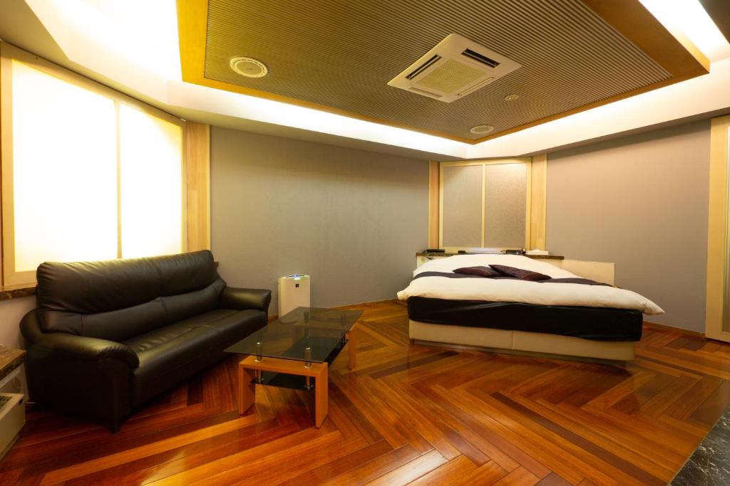 - une chambre avec un lit et un canapé en cuir dans l'établissement HOTEL Rplus日高, à Hidaka