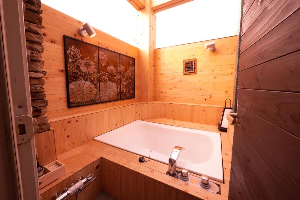 une salle de bain avec baignoire dans une pièce en bois dans l'établissement HOTEL Rplus日高, à Hidaka