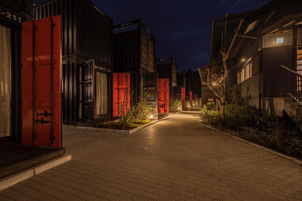 une rue vide la nuit avec des portes rouges et des bâtiments dans l'établissement HOTEL R9 Kujukuri "ex Casual Resort COFF Ichinomiya", à Ichinomiya