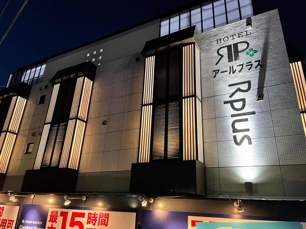 un bâtiment avec une enseigne sur la façade dans l'établissement HOTEL Rplus日高, à Hidaka