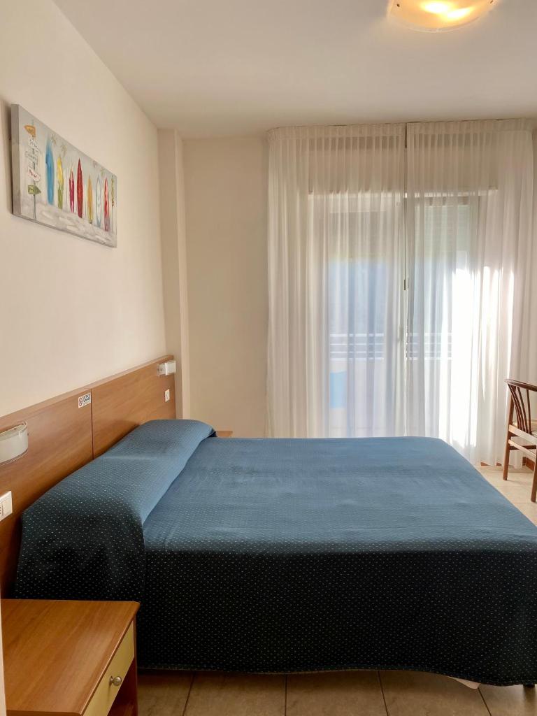 une chambre avec un lit bleu et une fenêtre dans l'établissement Hotel Ivana, à Lido di Jesolo