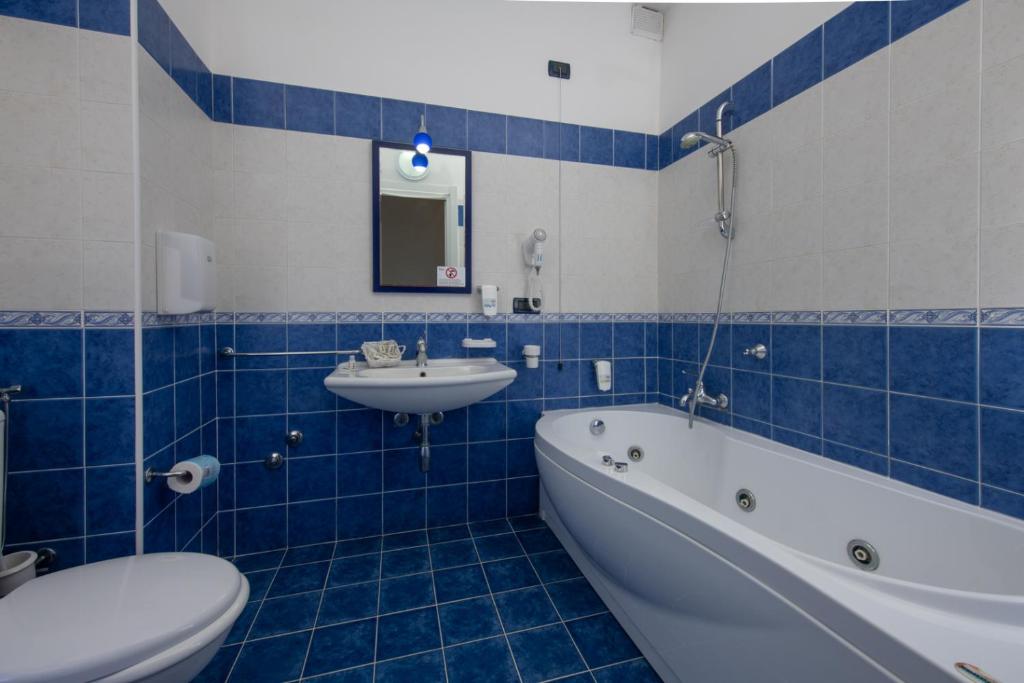 une salle de bains avec lavabo, baignoire et toilettes dans l'établissement Hotel Baia D'oro, à Licata