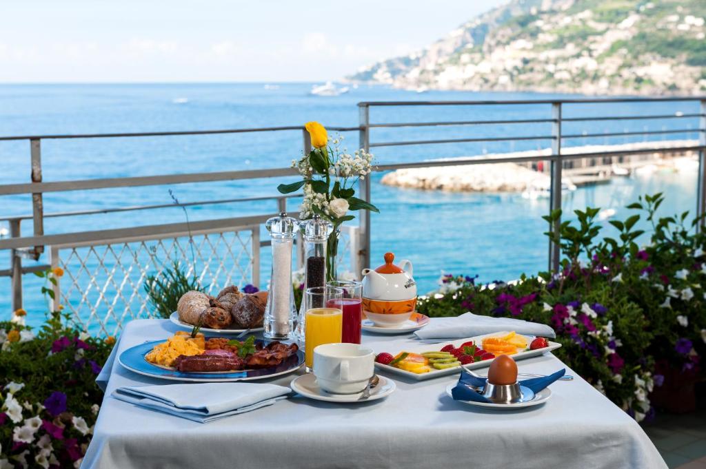 une table avec de la nourriture dessus avec vue sur l'océan dans l'établissement Hotel Panorama, à Maiori