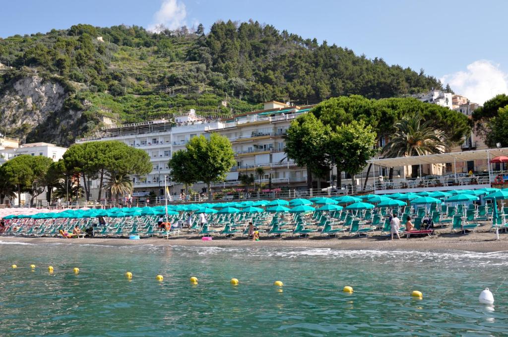 une plage avec des chaises et des parasols et un hôtel dans l'établissement Hotel Panorama, à Maiori