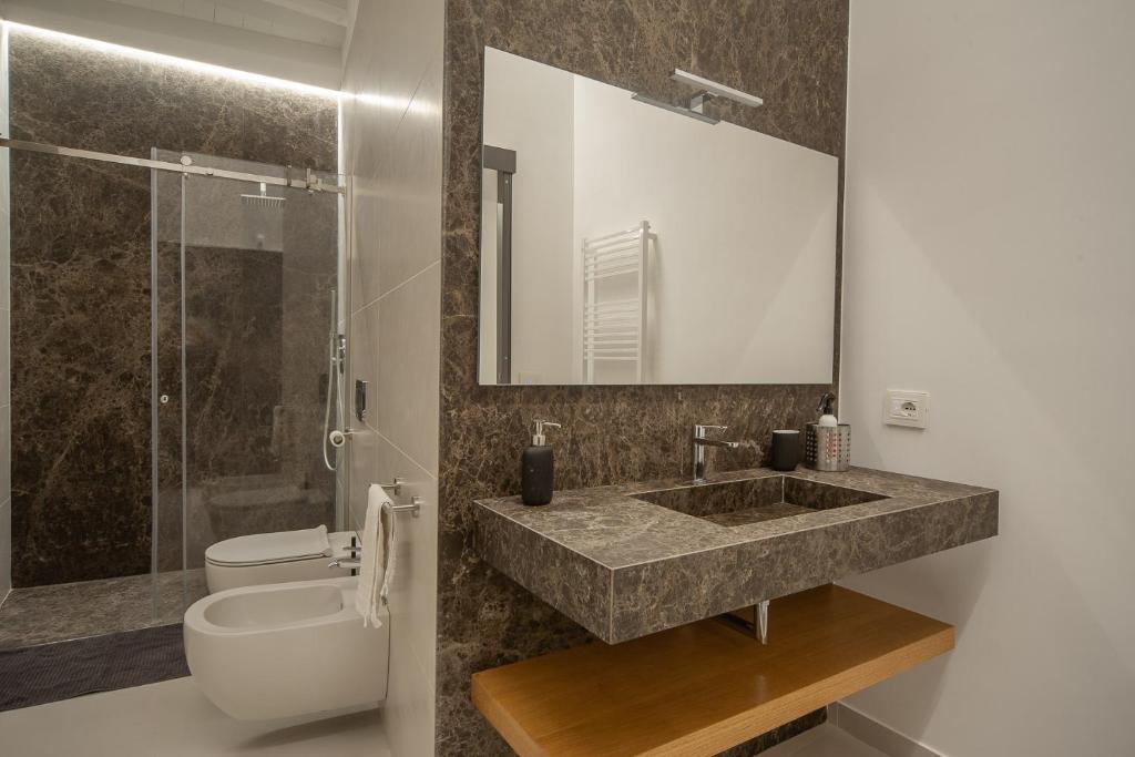 une salle de bain avec un lavabo, des toilettes et un miroir dans l'établissement Mori Siciliani House, à Aci Castello