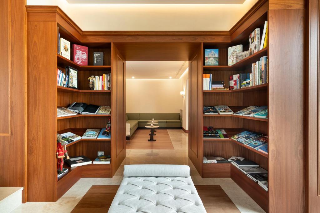 une bibliothèque avec des étagères en bois et un banc au milieu dans l'établissement Il San Corrado di Noto, à Noto