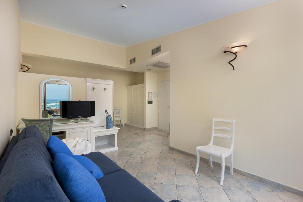 un salon avec un canapé bleu et une chaise dans l'établissement Hotel Riviera, à San Vito Lo Capo