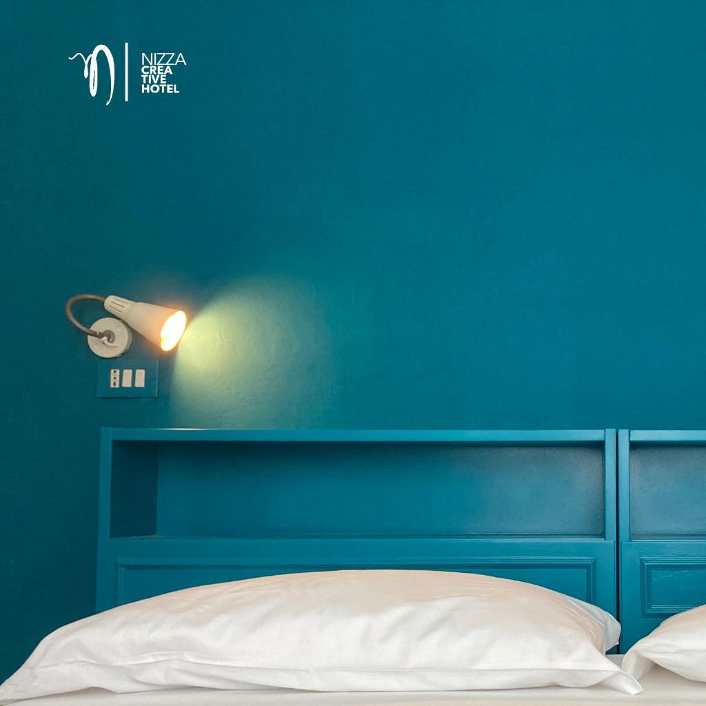 - une chambre bleue avec un lit et un mur bleu dans l'établissement Hotel Nizza Creative Hotel, à Rimini