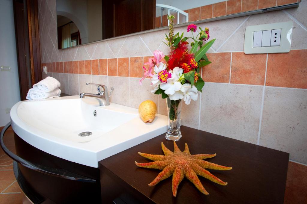 La salle de bains est pourvue d'un lavabo avec un vase de fleurs et une étoile de mer. dans l'établissement Villa Cedrino, à San Teodoro