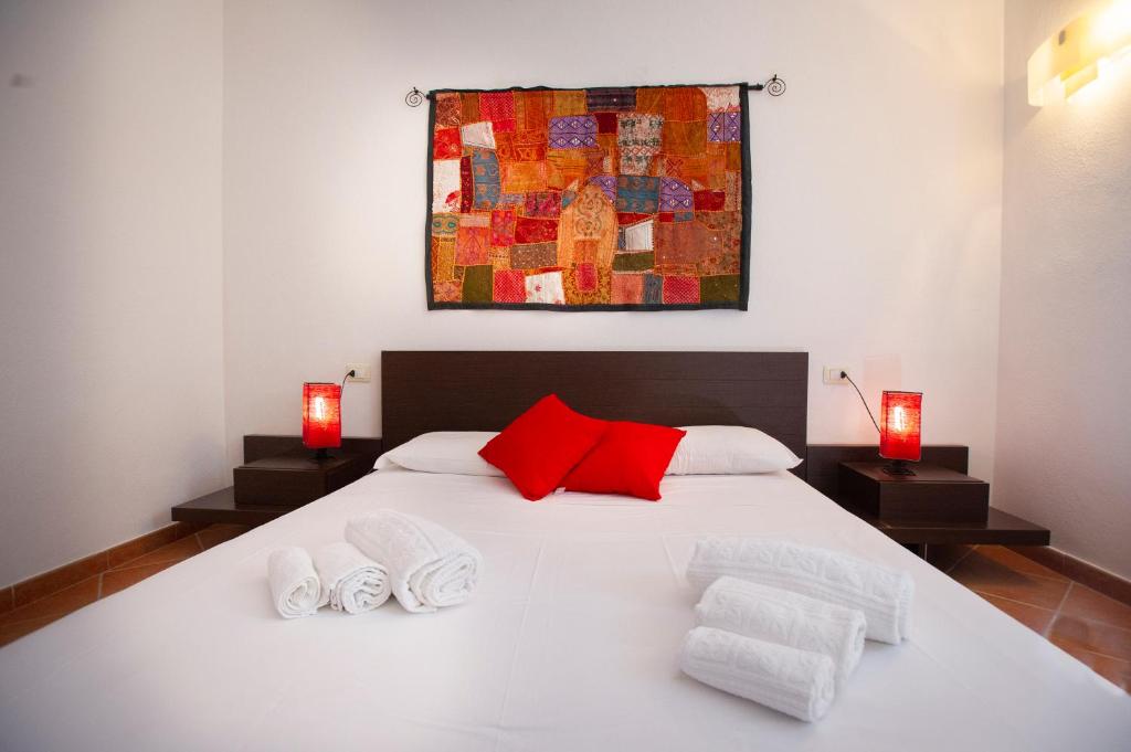 - une chambre avec un lit blanc et 2 oreillers rouges dans l'établissement Villa Cedrino, à San Teodoro