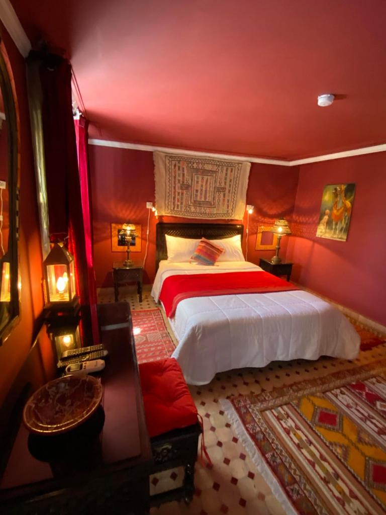 une chambre avec un grand lit aux murs rouges dans l'établissement Riad Jean Claude, à Fès