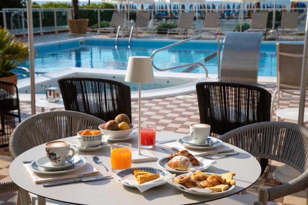 - une table avec de la nourriture pour le petit-déjeuner à côté de la piscine dans l'établissement Hotel Mirafiori, à Lido di Jesolo