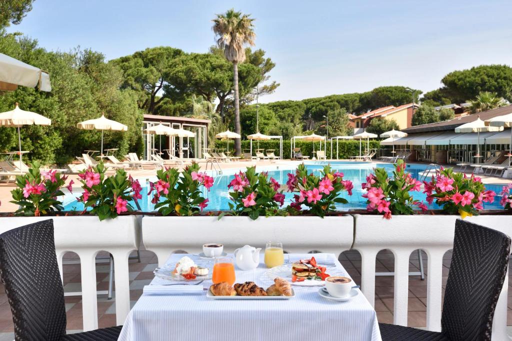 une table avec de la nourriture dessus à côté d'une piscine dans l'établissement Park Hotel Marinetta - Beach & Spa, à Marina di Bibbona