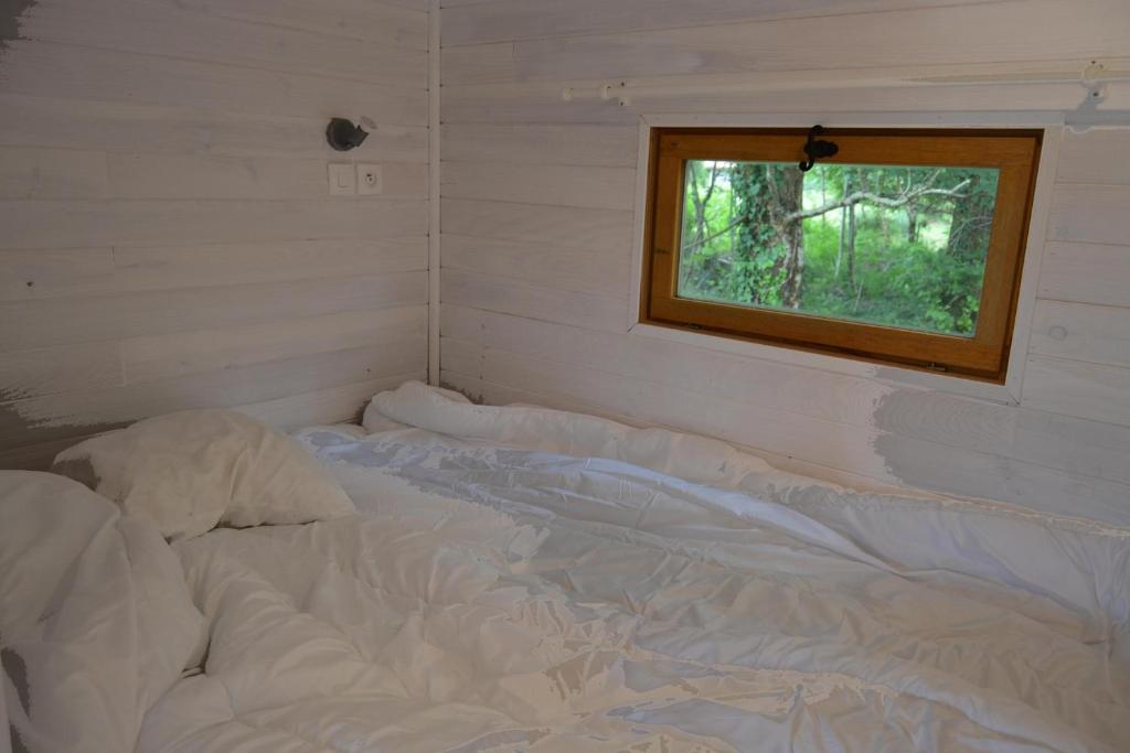 - un lit non aménagé dans une chambre avec fenêtre dans l'établissement Roulotte paisible au milieu de la nature, à Sainte-Eulalie-en-Born 2 autres photos