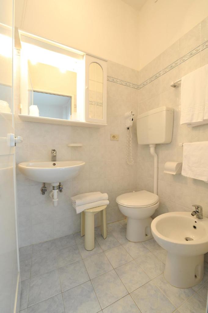 une salle de bain blanche avec un lavabo et des toilettes dans l'établissement Hotel Savoia, à Lido di Jesolo
