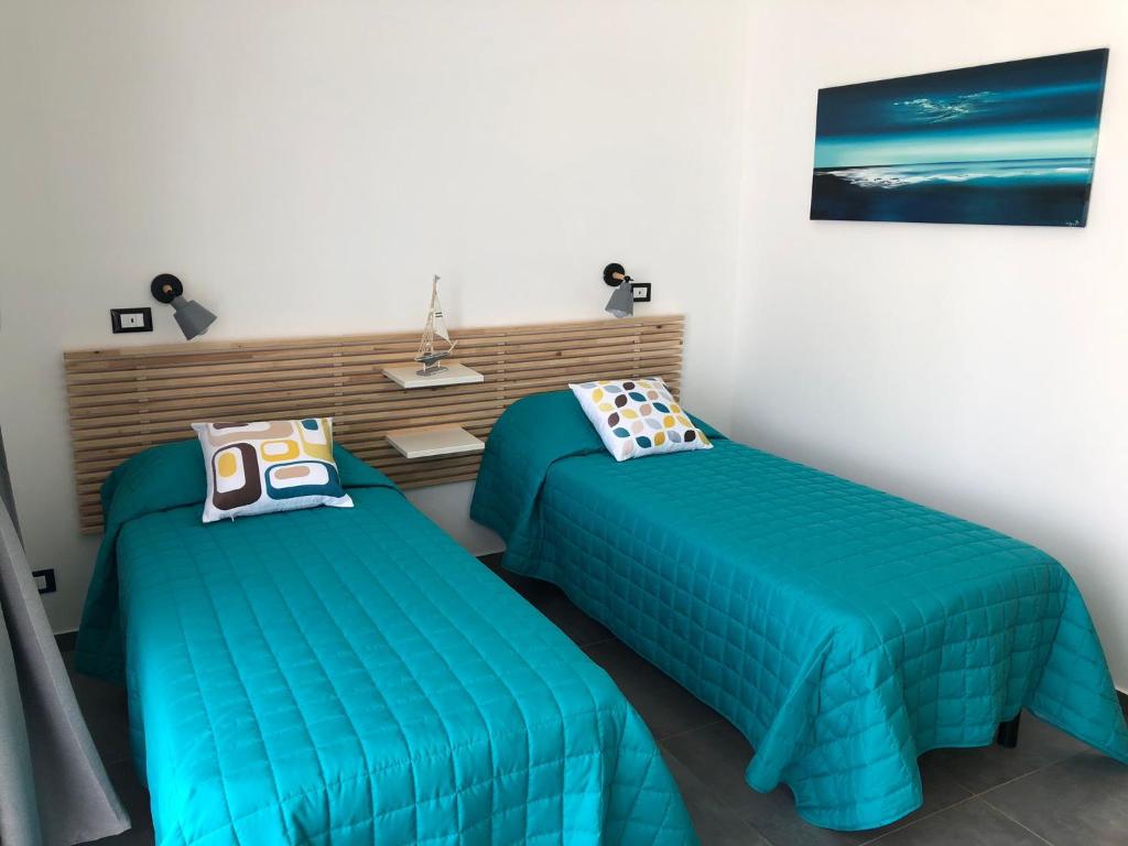 - 2 lits dans une chambre avec des couettes bleues dans l'établissement La Perla Bianca, à Porto Palo