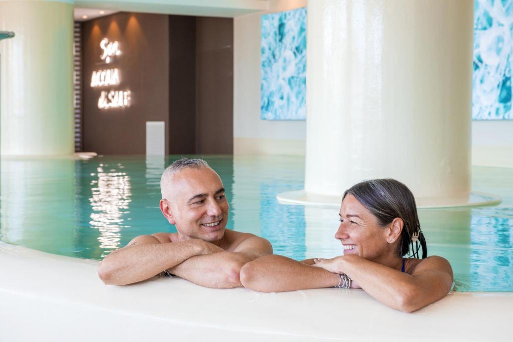 un homme et une femme qui se posent dans une piscine dans l'établissement Grand Hotel Terme, à Margherita di Savoia