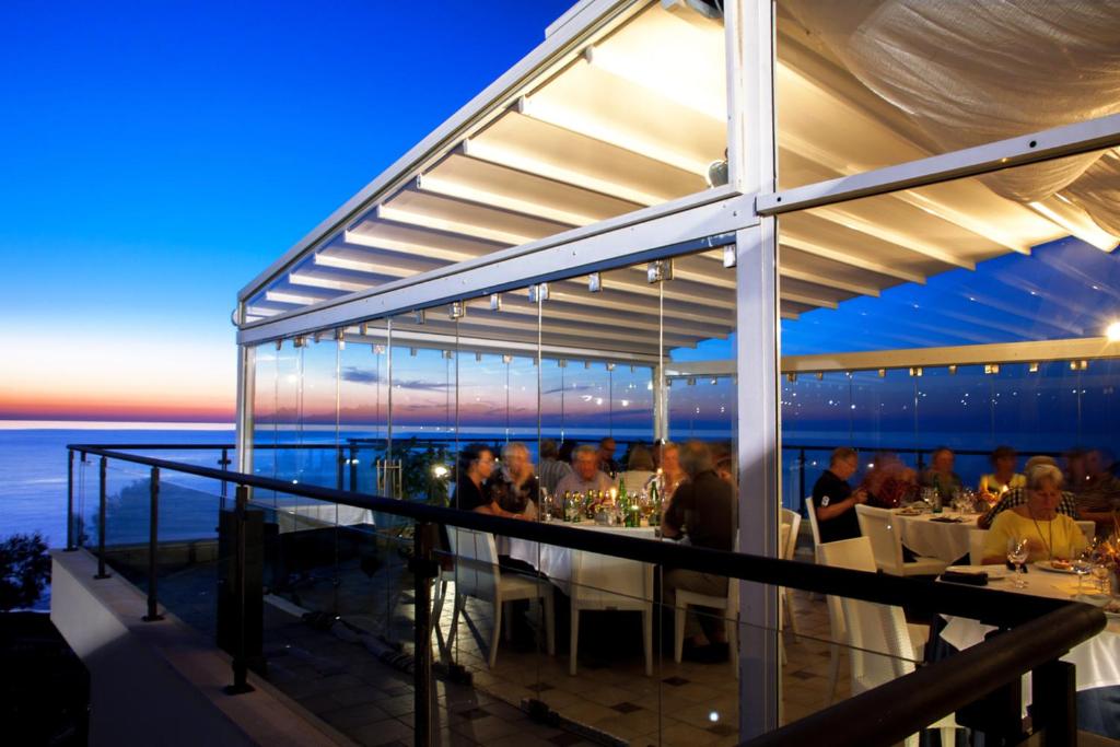 un groupe de personnes assises dans un restaurant sur un balcon dans l'établissement Cefalù Sea Palace, à Cefalù