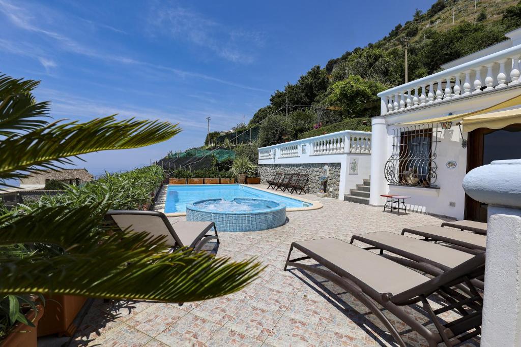 une terrasse avec des chaises, une piscine et une maison dans l'établissement Villa Elena, à Conca dei Marini