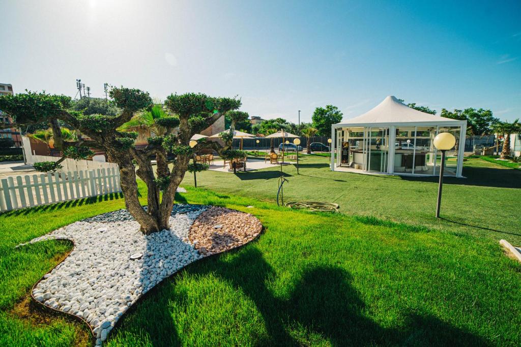 un arbre au milieu d'une cour avec un bâtiment dans l'établissement Hotel Park, à Sottomarina