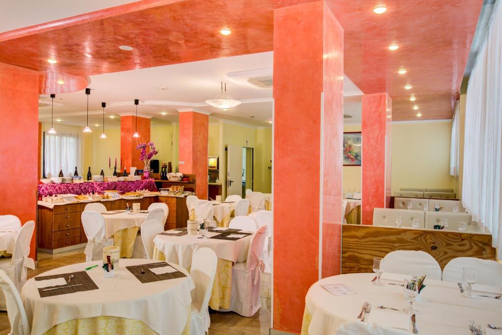un restaurant avec des tables blanches et des chaises blanches dans l'établissement Hotel Dusseldorf, à Rimini