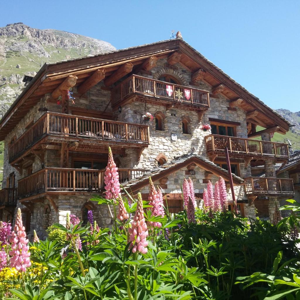 une cabane en rondins avec des balcons et des fleurs devant elle dans l'établissement Chalet l'Avalin, à Val dʼIsère