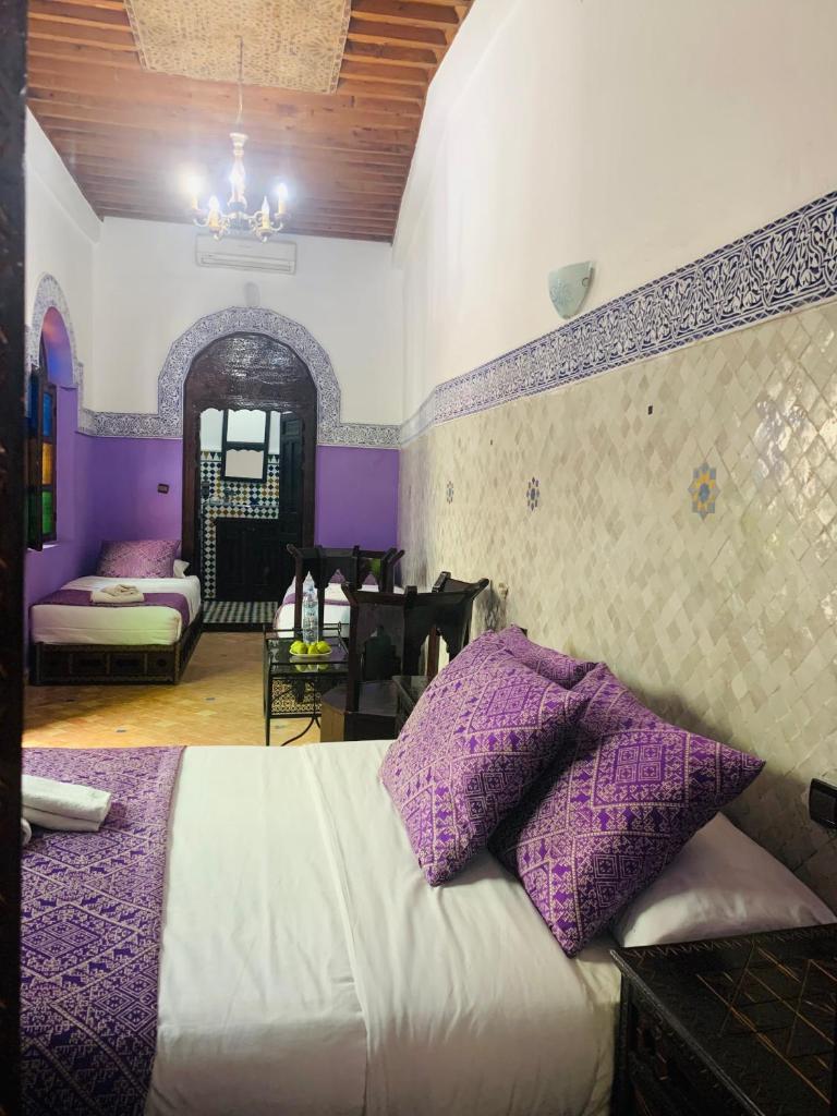 - une chambre avec des murs violets et un lit avec des oreillers violets dans l'établissement Riad Zahraa Al Ismailia, à Meknès