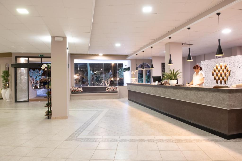 une femme assise au comptoir dans un hall dans l'établissement Hotel Club Eloro, à Noto Marina