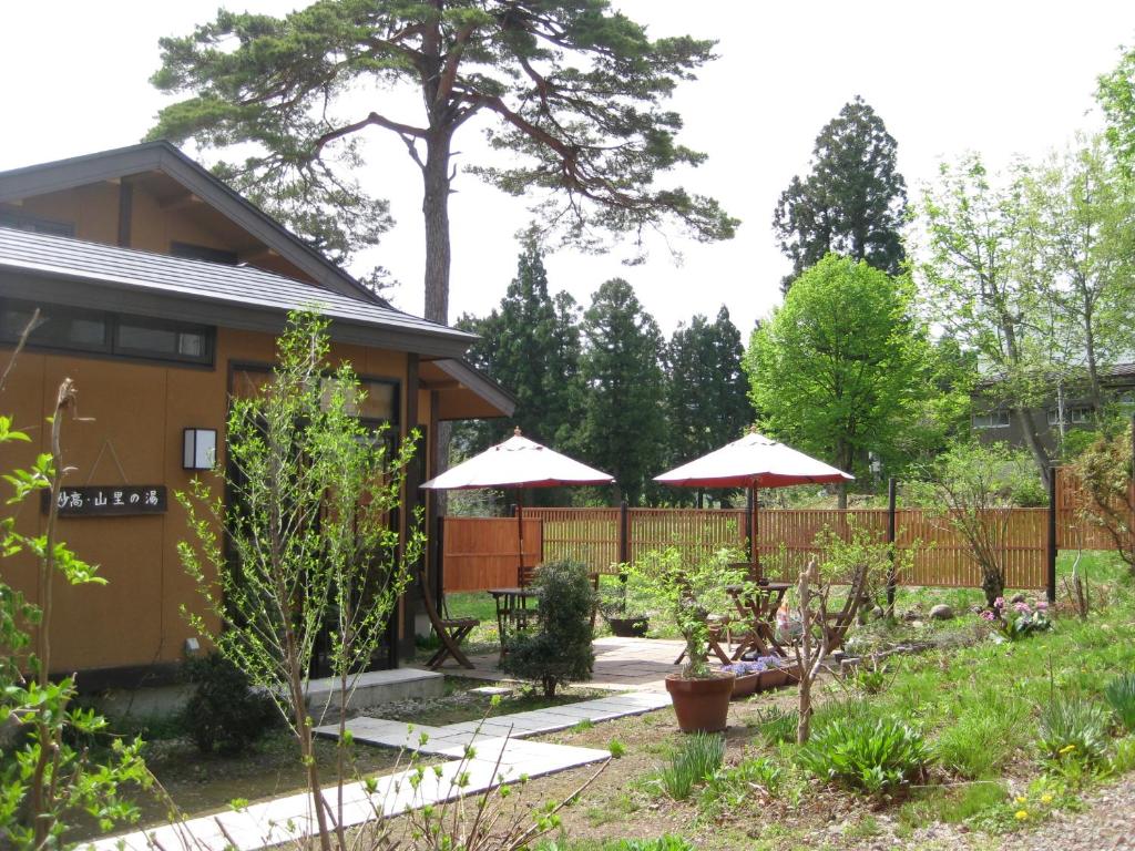 un jardin avec deux parasols et une maison dans l'établissement Kofukan, à Myōkō