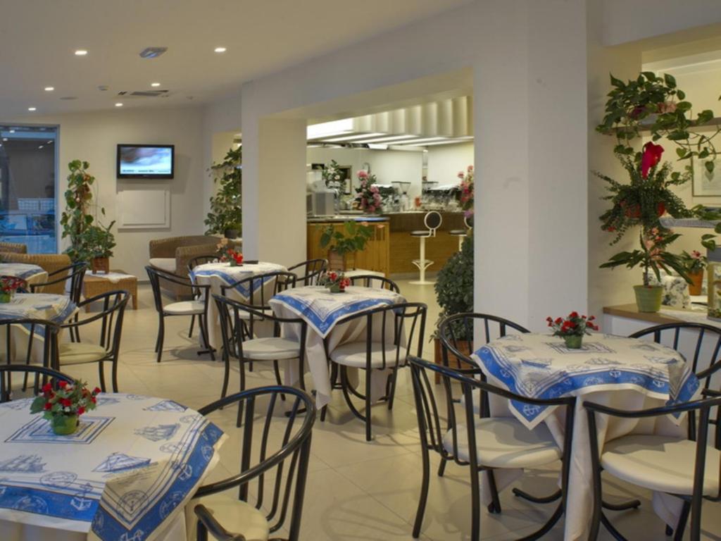 un restaurant avec des tables et des chaises avec des fleurs dessus dans l'établissement Hotel Nives, à Riccione