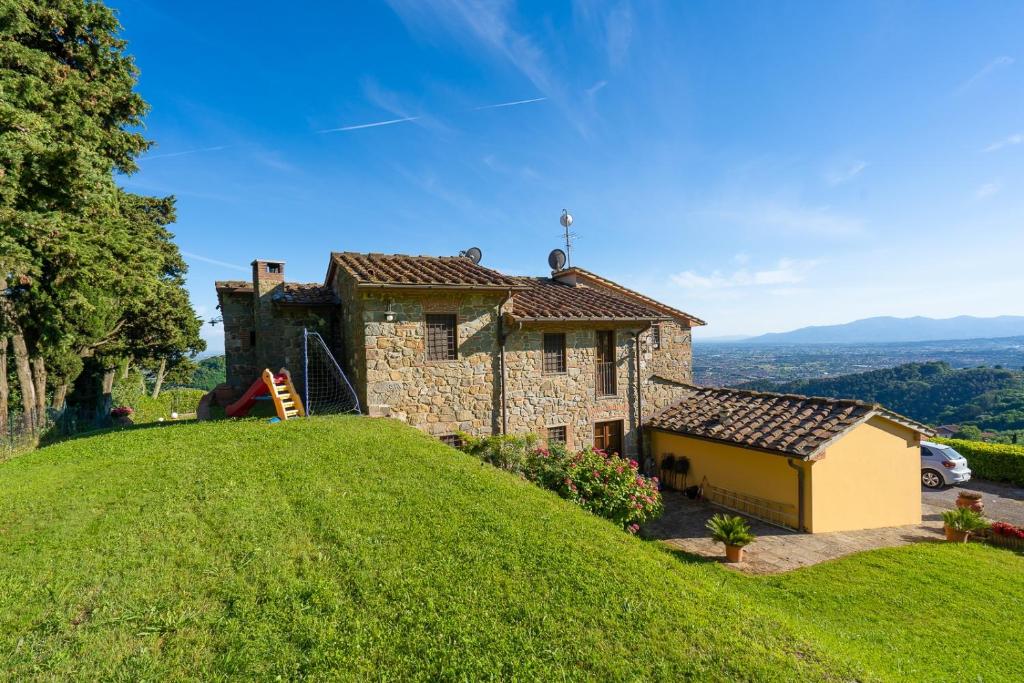 une maison en pierre au sommet d'une colline herbeuse dans l'établissement Casa Loretta, your luxurious getaway with stunning views, à Nievole