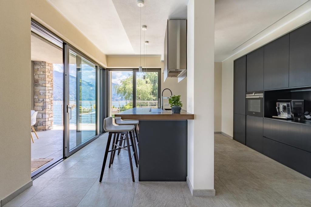 une cuisine avec des placards noirs et un comptoir avec des tabourets dans l'établissement Villa Del Sasso - Cremia, à Cremia