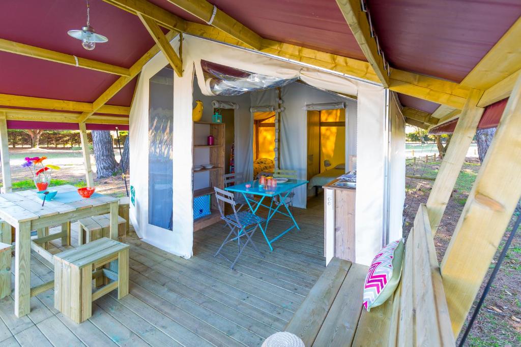 une terrasse couverte d'une maison avec une table et des chaises dans l'établissement Camping Le Fou du Roi, à Lansargues