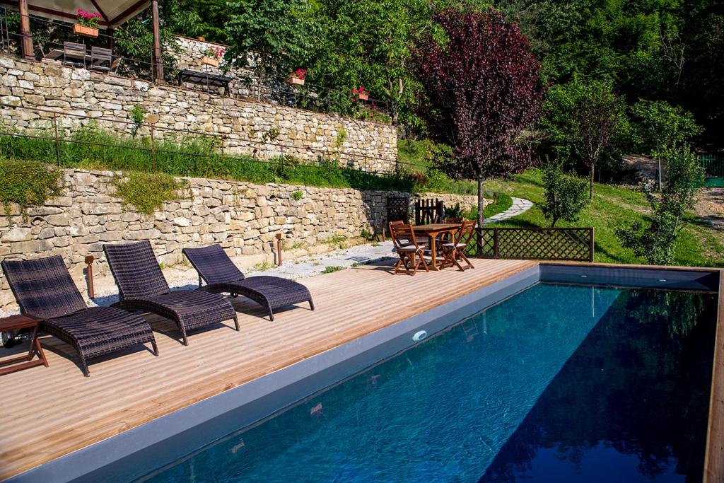 une piscine avec quatre chaises, une table et une terrasse en bois dans l'établissement VILLA ANCORA Tenuta Lonciano, à Gualdo