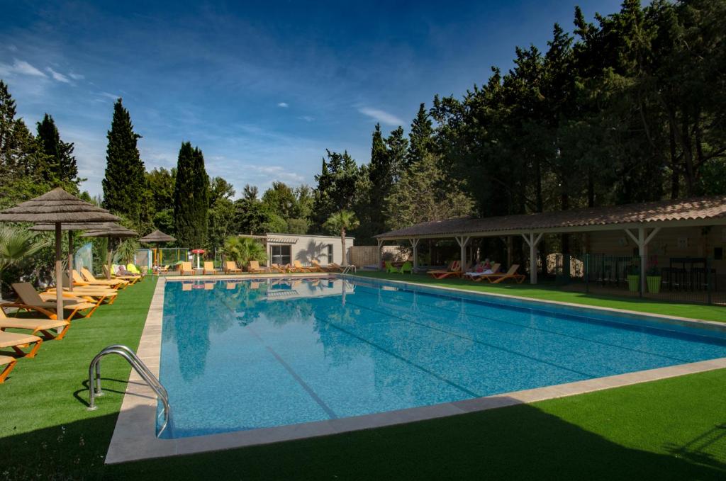 une grande piscine avec chaises et parasols dans l'établissement Les hebergements Insolites, à Taradeau