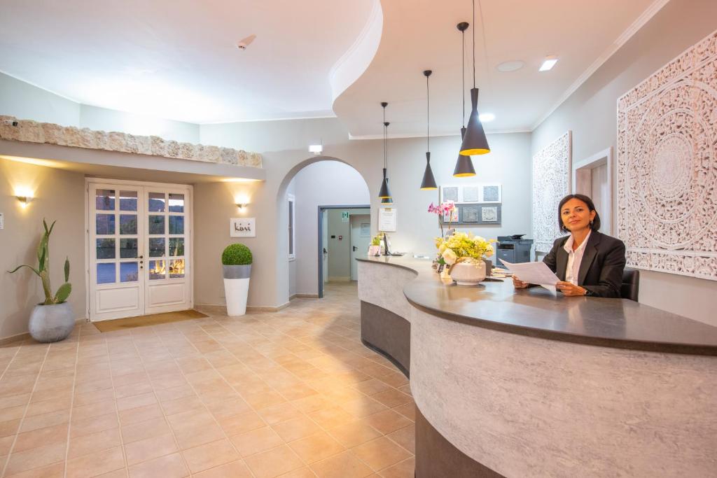 une femme assise à un comptoir dans une cuisine dans l'établissement Hotel Baia D'oro, à Licata