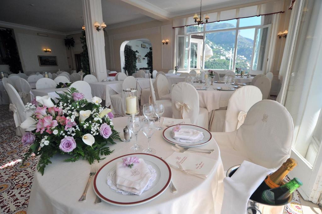 une salle à manger avec des tables blanches et des chaises blanches dans l'établissement Hotel Belvedere, à Conca dei Marini 210 autres photos