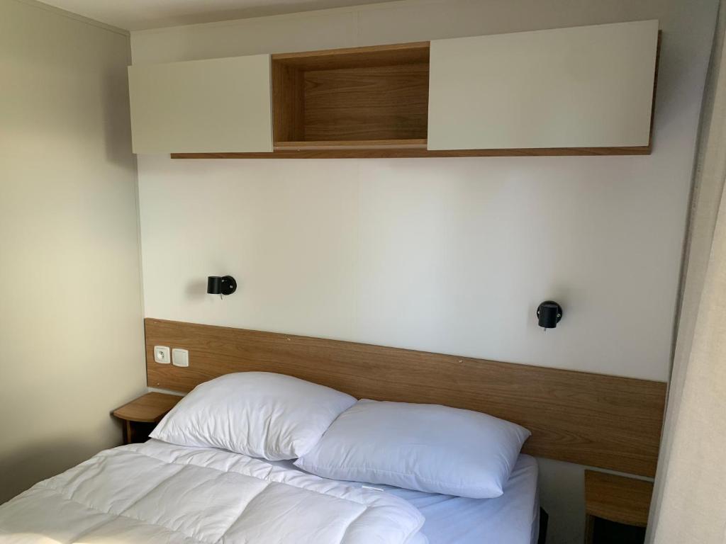 un lit avec des draps blancs et une tête de lit en bois dans l'établissement Mobil-home Dan Dom, à Saint-Hilaire-de-Riez 6 autres photos