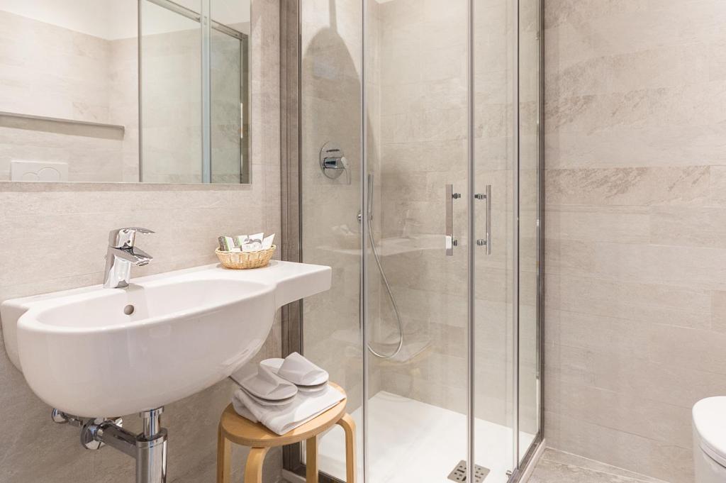 une salle de bain blanche avec lavabo et douche dans l'établissement Hotel Tirreno, à Spotorno