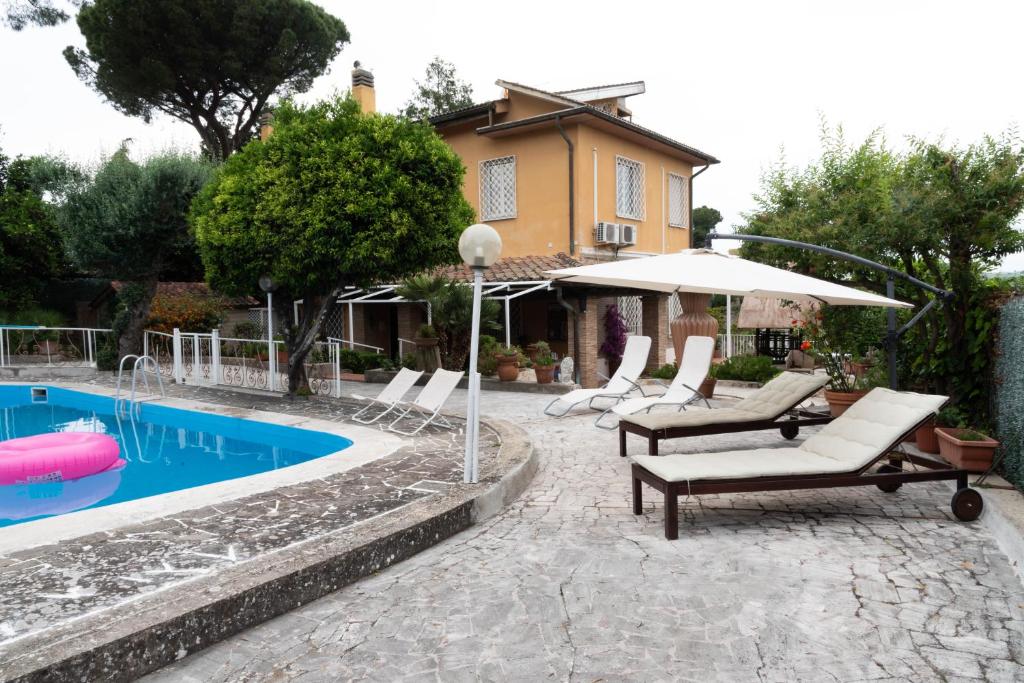- un groupe de chaises et un parasol à côté de la piscine dans l'établissement Villa Amalia Augusta, à Anguillara Sabazia