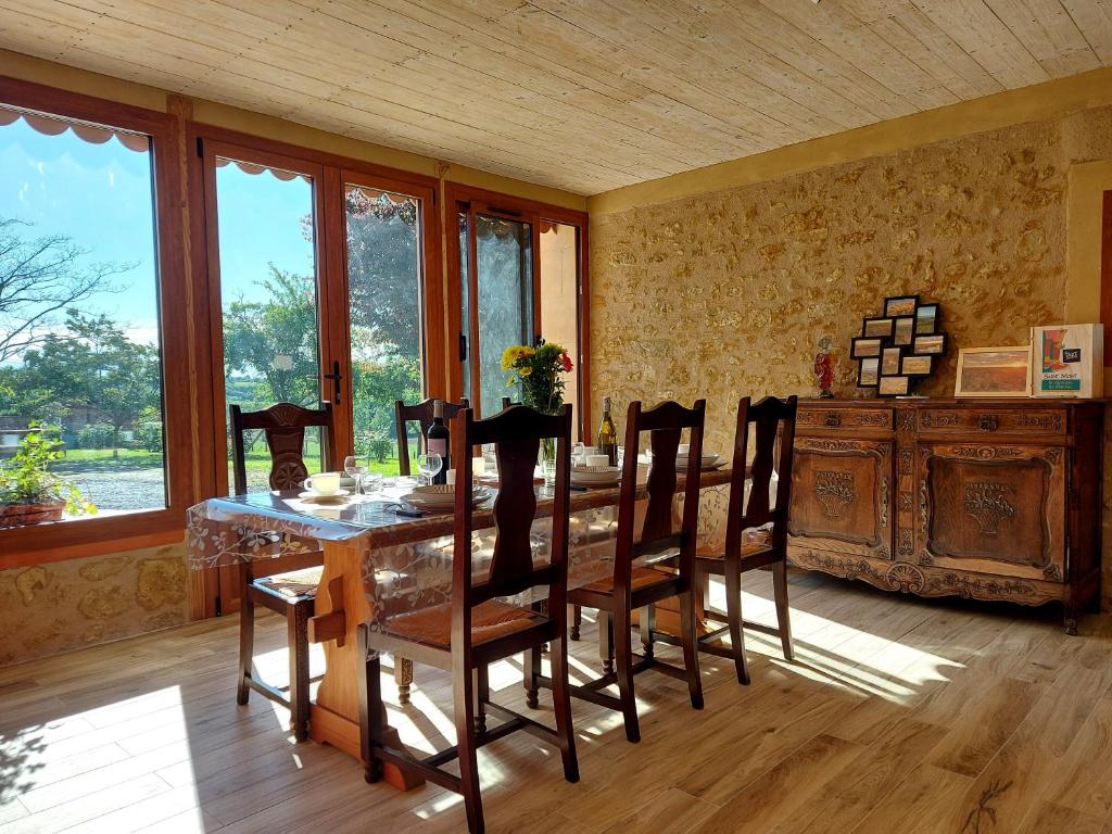 une salle à manger avec une table, des chaises et des fenêtres dans l'établissement Gite La Saubolle à Marciac, à Marciac