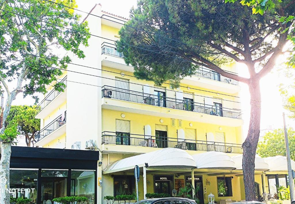 un grand bâtiment jaune avec un balcon dans une rue dans l'établissement Hotel Garisenda B&B - in Centro a Riccione -, à Riccione