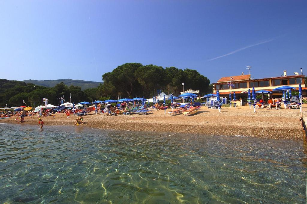 - une plage avec un groupe de personnes assises sur la plage dans l'établissement Frank's Hotel, à Capoliveri